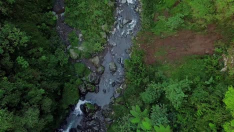Aerial-flyover-river-stream-floating-between-rocks-in-jungle-of-Indonesia-during-daytime---Kedung-Kayang-Waterfall-Central-Java