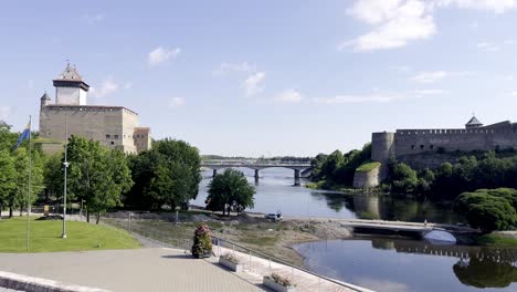 Border-between-Estonia-and-Russia-in-summer-2022---Establishing-shot-with-two-castles-along-the-river-of-Narva-connected-by-a-road-bridge