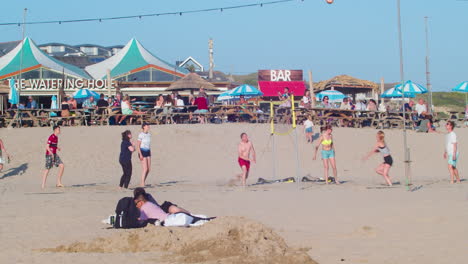 Gente-Jugando-Voleibol-En-La-Playa-De-Perranporth-Con-Pub-Al-Fondo-En-Cornualles,-Reino-Unido