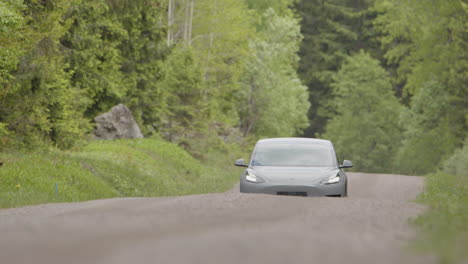Lange-Linsenfront-–-Ein-2020-Tesla-Model-3-Fährt-Eine-Bewaldete-Unbefestigte-Straße-Entlang