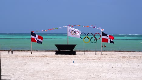 Olympic-flag-waves-between-Dominican-Republic-Flags-on-tropical-beach