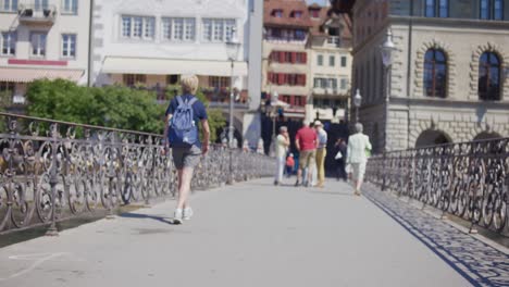 Older-women-walking-across-downtown-bridge-among-tourists-in-Luzern,-Switzerland
