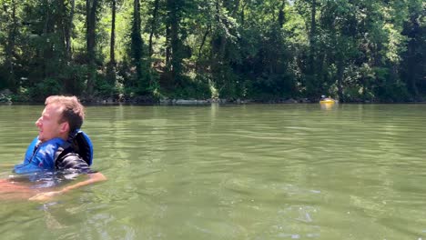 Static-shot-of-a-couple-enjoying-river-tubing-surrounded-by-lush-green-trees-on-a-sunny-day