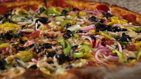 Vegetables-cover-top-of-large-supreme-pizza,-close-up-slider-4K