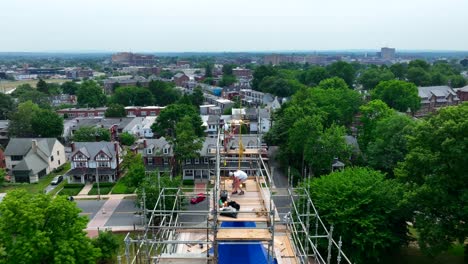 Rising-aerial-shot-of-hard-working-employees-high-atop-scaffolding-as-they-perform-repairs-an-maintenance-on-an-old,-Victorian-era--church-building