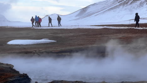 Tourists-People-Walking-Exploring-Mývatn-Geothermal-Area-in-Iceland,-Natural-Geological-Site-in-Winter,-Volcanic-Fumarole-Craters-Steaming,-Vapor-Steam-Gas-and-Thermal-Heat