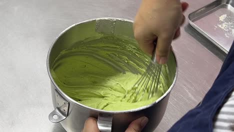 Professional-pastry-chef-hand-mixing-matcha-green-tea-flavor-cake-mixture,-preparing-to-make-tasty-traditional-Japanese-dessert,-close-up-shot