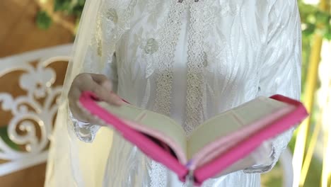 Close-up-of-the-open-Quran-in-the-hands-of-a-young-muslim-girl