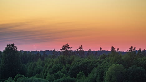 Zeitrafferaufnahme-Eines-Feuergelben-Himmels-Bei-Sonnenaufgang-Mit-Vorbeiziehenden-Zirruswolken-über-Einer-Grünen-Waldlandschaft
