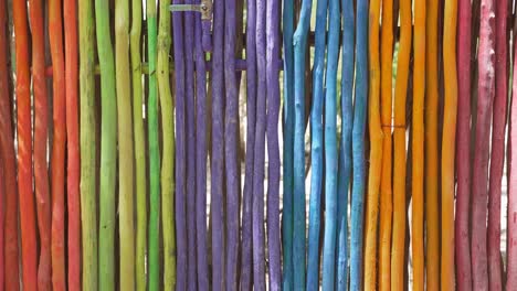 Beautiful-Colorful-Rainbow-Fence-Made-Of-Wooden-Branches-Posted-Vertically-During-Sunny-Summer-Day