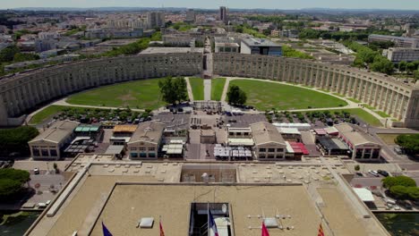 Beautiful-aerial-perspective-of-Montpellier,-France-with-the-French-and-European-etc-flags-on-top-of-a-roof-of-a-big-building