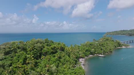 Drohnenaufnahme-Einer-Tropischen-Insel,-Parkende-Boote-In-Der-Bucht-Und-Brücke-Im-Hintergrund-An-Sonnigen-Sommertagen---Bahia-De-Samana,-Dom