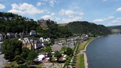 Aerial-flying-drone-shot,-tracking-in,-of-the-Rhine-River-Valley-coast-line-and-Old-Architecture---including-medieval-castles,-old-buildings,-and-natural-forested-alpine-hills