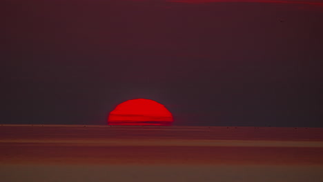 Die-Orangefarbene-Sonne-Versinkt-Bei-Sonnenuntergang-Hinter-Dem-Horizont-Des-Ozeans-–-Zeitraffer