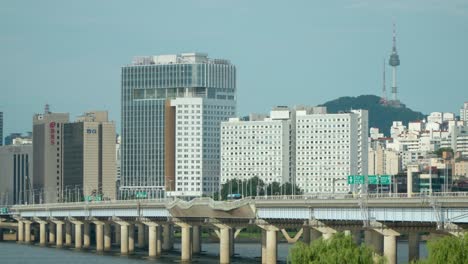 Traffic-on-Mapo-Bridge-over-Hangang-River-with-a-view-of-skyscrapers-and-financial-towers,-N-Seoul-Namsan-tower-in-background