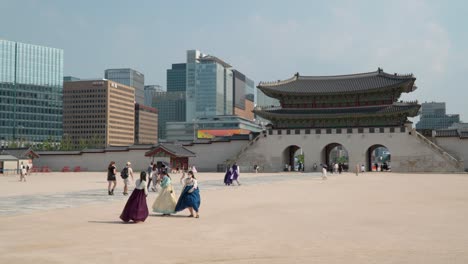 Locals-And-Tourists-In-Hanbok-Costume-At-Gyeongbokgung-Palace-With-Gwanghwamun-Gate-And-Seoul-Skyline-In-The-Background-In-South-Korea