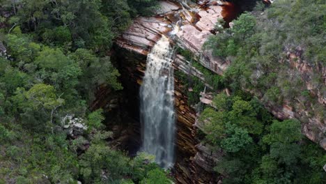 Aerial-drone-tilting-down-shot-of-the-incredible-Mosquito-Falls-surrounded-by-tropical-jungle-and-cliffs-in-the-Chapada-Diamantina-National-Park-in-Northeastern-Brazil-on-a-warm-sunny-summer-day