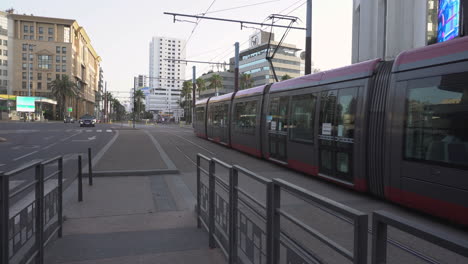 Der-Rote-Trolley-Von-Casablanca-Fährt-über-Eine-Kreuzung,-Autos-Stehen-An-Der-Haltestelle,-Ende-Des-Abdelmoumen-Boulevards,-Eröffnungsaufnahme