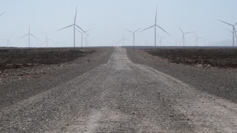 The-image-shows-a-trail-in-the-middle-of-the-desert-leading-to-a-wind-farm