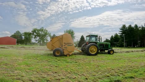 John-Deere-tractor-pulling-a-Vermeer-hay-baler-along-alfalfa-windrows-to-make-round-hay-bales