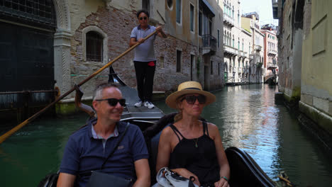Pareja-De-Turistas-Recorriendo-La-Ciudad-De-Venecia,-Montando-Una-Góndola-Veneciana-En-Italia