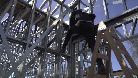 Un-Trabajador-En-Una-Escalera-Construyendo-El-Marco-De-Acero-Para-Una-Casa---Cerrar