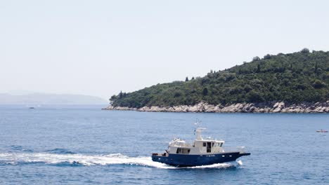 Fishing-boat-going-out-to-the-sea-to-fish-with-the-Otok-Lokrum-island-in-the-background-in-Dubrovnik,-Croatia