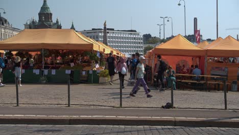 People-explore-outdoor-food-market-tent-stalls-on-Finland-summer-day