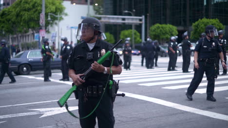 A-policeman-in-riot-gear-stands-at-attention-while-holding-a-rubber-bullet-rifle-at-a-BLM-protest-in-Downtown