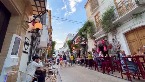 Menschen-Sitzen-Und-Essen-Draußen-In-Restaurants-In-Der-Altstadt-Von-Marbella,-Spanien,-Belebte-Romantische-Straße-Im-Sommer,-Touristen-Zu-Fuß,-4K-Aufnahme