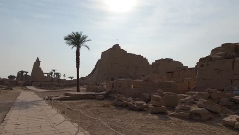 Turistas-Caminando-Por-Palmera-En-Las-Ruinas-Del-Templo-De-Karnak,-Luxor,-Egipto