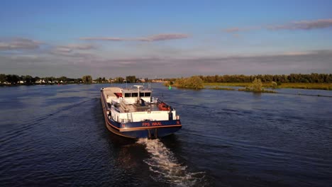 Aerial-Drone-Stern-View-Of-FPS-Waal-Inland-Cargo-Vessel-Along-Oude-Maas-With-During-Golden-Hour