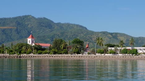 The-historic-Church-de-Santo-António-de-Motael,-oldest-Roman-Catholic-church-from-waterfront-with-daily-city-traffic-in-the-capital-Dili,-Timor-Leste,-Southeast-Asia