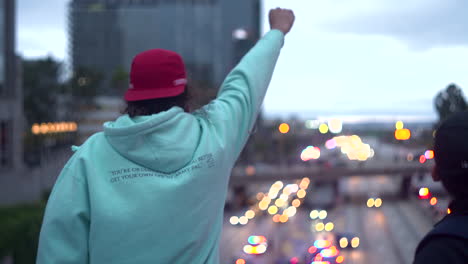 A-Man-holds-up-his-fist-towards-traffic-on-the-110-highway-during-a-BLM-protest-in-Downtown