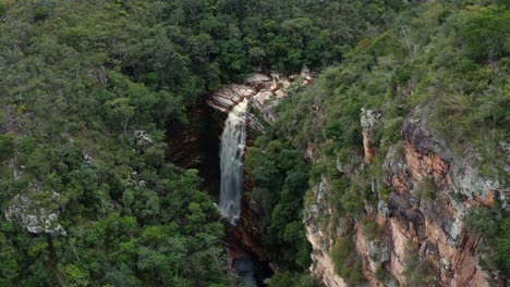 Aerial-drone-dolly-in-tilting-down-shot-of-the-incredible-Mosquito-Falls-surrounded-by-tropical-jungle-and-cliffs-in-the-Chapada-Diamantina-National-Park-in-Northeastern-Brazil-on-a-sunny-summer-day