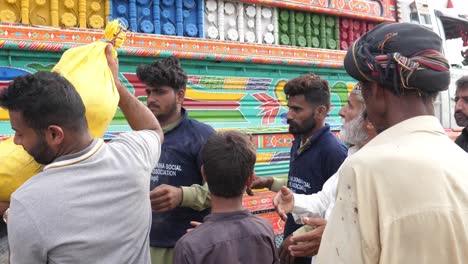 Helfer-Heben-Gelben-Sack-Neben-LKW-Während-Hochwasserhilfeprogramm-In-Belutschistan