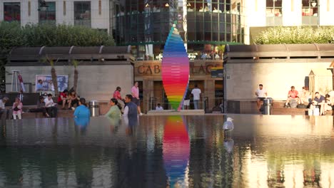 Canary-Wharf-London-England-June-2022-Pride-tribute-sculpture-rotating-by-the-Cabot-Square-fountain-with-the-reflection-playing-back-across-the-water