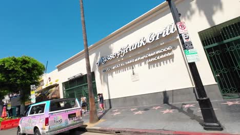 POV-car-driving-along-sunny-famous-Hollywood-boulevard-shops-and-businesses