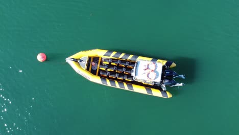 Empty-SEAWAKE-tourist-sightseeing-speed-boat-aerial-rising-Birdseye-view-floating-on-calm-shimmering-waves