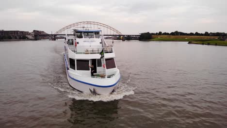 Aerial-Parallax-Around-Forward-Bow-Of-Smaragd1-Party-ship-Going-Past-On-River-Noord