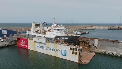 Eine-Seitliche-Luftaufnahme-Eines-Fischtrawlers,-Der-In-Einem-Trockendock-Für-Reparatur--Und-Lackierarbeiten-In-Hanstholm-Aus-Dem-Wasser-Gehoben-Wurde