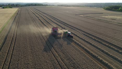 Combine-Harvester-Loading-Grain-in-Chaser-Bin-Wagon-With-Tractor-on-Agricultural-Field,-Food-Industry-Concept,-Drone-Aerial-View