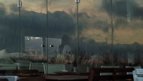 Chica-Bailando-Mientras-Entra-En-Un-Club-De-Puesta-De-Sol-Con-Reflejos-De-Nubes-En-La-Ventana-En-Costa-Da-Caparica,-Portugal