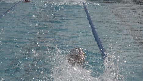 Toma-En-Cámara-Lenta-De-Un-Nadador-Que-Está-Nadando-Entre-Los-Carriles-De-La-Piscina-Lo-Más-Rápido-Que-Puede