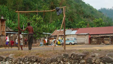 children-playing-football-in-front-of-the-slum-houses-in-an-African-village-next-to-the-jungle---wide-shot