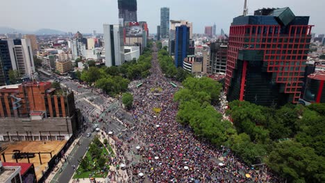 Huge-amount-of-people-gathered-on-Reforma-avenue,-during-Pride-in-Mexico-city---tilt,-aerial-view