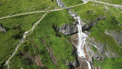 Waterfall-in-the-swiss-alps,-water-from-the-glacier-flows,-cascade-near-green-meadows
