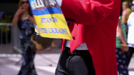 A-Man-holds-up-a-sign-that-says-"Hollywood-Stands-with-Ukraine,"-while-holding-an-Oscar