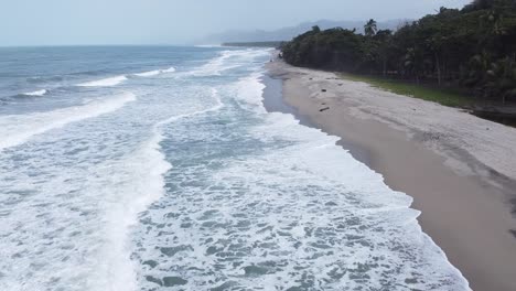 Caribbean-sea-waves-break-onto-long-white-sandy-beach-in-tropical-haze