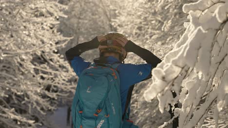 Skifahrender-Mann,-Der-Seine-Schutzbrille-Im-Weißen,-Verschneiten-Wald-Festzieht